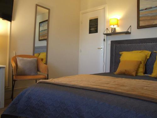 a bedroom with a large bed and a chair at La Villa Port Winston - Face Mer B&B in Saint-Côme-de-Fresné