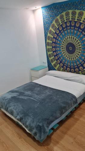 uma cama num quarto com uma tapeçaria na parede em Rosa de los Vientos: Estudios em Cádiz