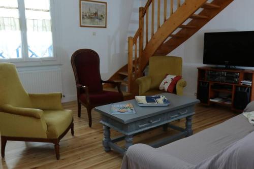 ein Wohnzimmer mit Stühlen, einem TV und einem Tisch in der Unterkunft La Rose des Sables maison de pêcheur de 7 pers. in Les Sables-dʼOlonne