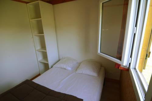 Habitación pequeña con cama y ventana en Les Chalets de Condrieu, en Condrieu