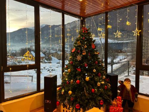 un arbre de Noël dans une chambre avec fenêtre dans l'établissement Hotel Mountain Mestia, à Mestia