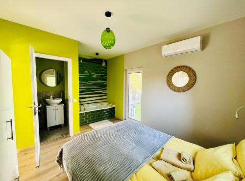 a bedroom with yellow walls and a bed and a bathroom at Babvirág Porta Fonyódliget in Fonyód