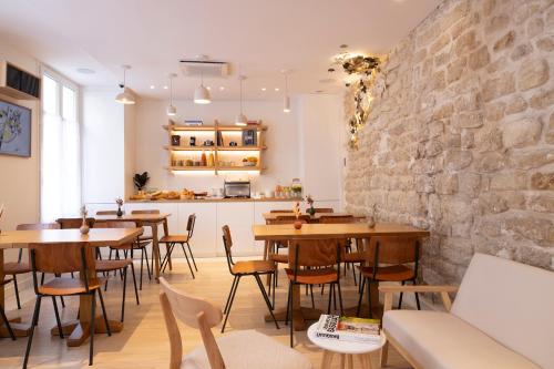 ein Restaurant mit Holztischen und -stühlen und Ziegelwand in der Unterkunft Hôtel Le Daum in Paris