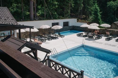 a swimming pool with umbrellas and tables and chairs at RUBEL APARTHOTEL&SPA in Yaremche