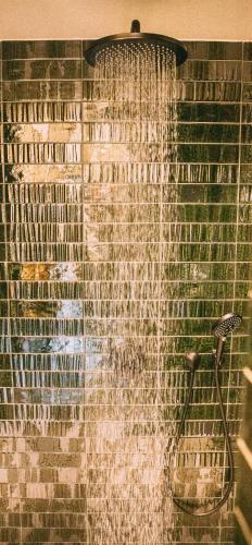 a shower with water coming out of a brick wall at de Wever Lodge in Otterlo