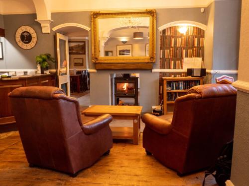 ein Wohnzimmer mit 2 Stühlen, einem Tisch und einem Spiegel in der Unterkunft Glan Aber Hotel in Betws-y-coed