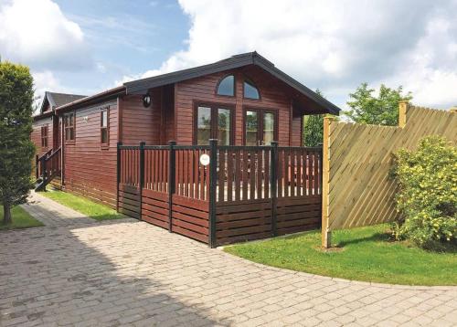a wooden house with a gate and a fence at Hollybrook Lodges in Easingwold