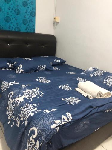 a bed with a blue and white blanket and pillows at Putri homestay Seaview pd in Port Dickson