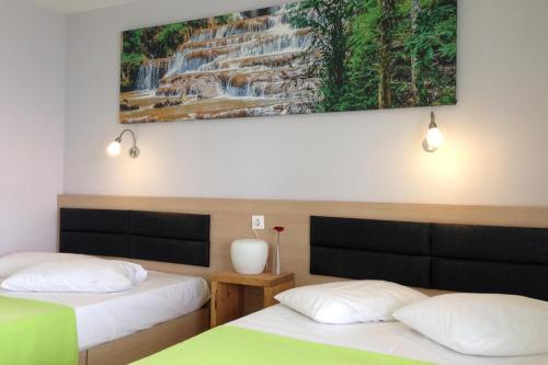 two beds in a room with a waterfall painting on the wall at Philoxenia Beach in Nea Vrasna
