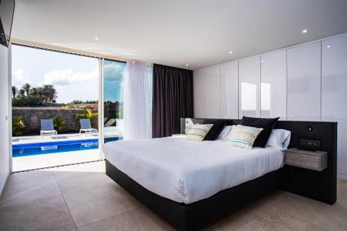 ein Schlafzimmer mit einem großen Bett und einem Balkon in der Unterkunft Golf Palms in Costa Teguise