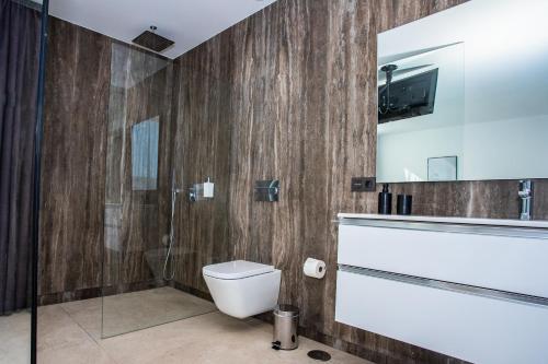 a bathroom with a toilet and a shower and a television at Golf Palms in Costa Teguise