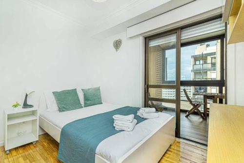 a white bedroom with a bed and a large window at Matosinhos Wonderfull apartment by Innkeeper in Matosinhos