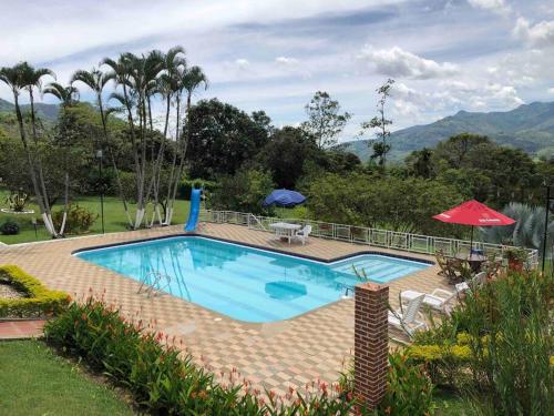 a swimming pool with a table and a red umbrella at Finca la Bonita, Barbosa, Antioquia. in Barbosa