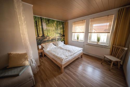 ein Schlafzimmer mit einem Bett und einem Stuhl sowie zwei Fenstern in der Unterkunft Helene in Vetschau
