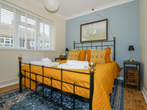 een slaapkamer met een bed met oranje lakens en een spiegel bij See The Sea in Hunstanton