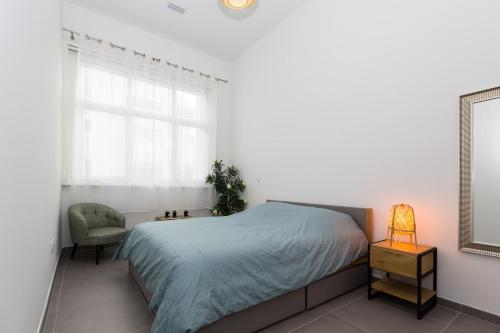 une chambre avec un lit, une chaise et un miroir dans l'établissement Le Mazenod - Appartement avec balcon à la Joliette, à Marseille