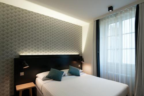 een slaapkamer met een bed met een groot raam en een witte sprei bij Hôtel Pax in Genève