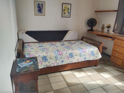 1 dormitorio con cama y mesa con colcha en Pituba quartos, en Salvador