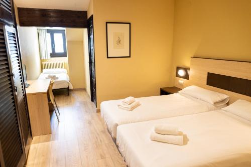 a hotel room with two beds and a desk at Hotel Port 1730 in La Coma i la Pedra