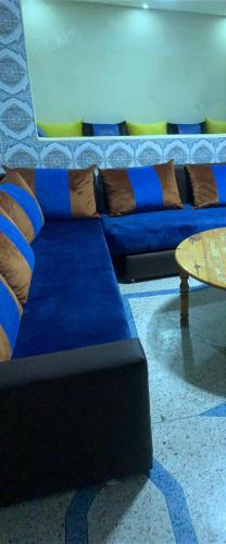 a blue couch with pillows and a table in a room at Appartement, tilila in Mirleft
