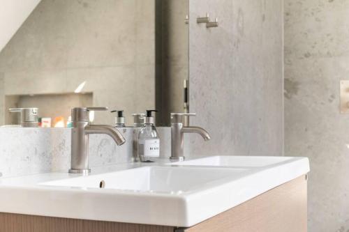 a bathroom with a white sink and a mirror at Villa Falsterbo - Beachside Luxury with Private Hot Tub in Skanör med Falsterbo