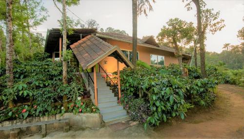 a house with a staircase leading up to it at Hiddenvalley Stays - Riverside in Madikeri
