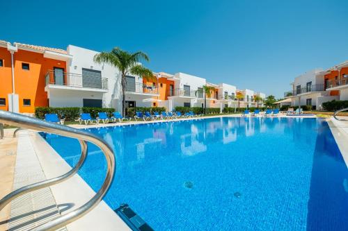 a large swimming pool with chairs and buildings at Jardins de Pêra in Pêra