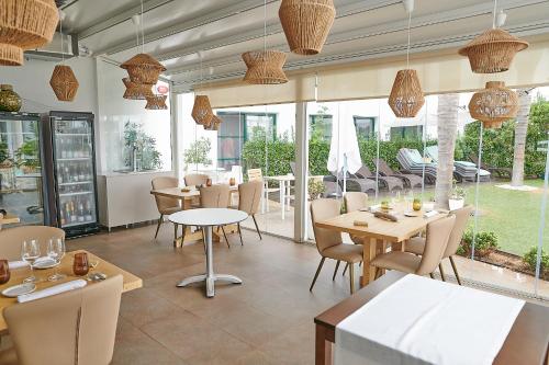 a restaurant with tables and chairs and windows at Hotel L'Algadir del Delta in Poblenou del Delta
