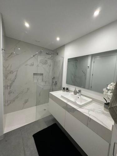 a white bathroom with a sink and a shower at Deluxe Bay View in Câmara de Lobos