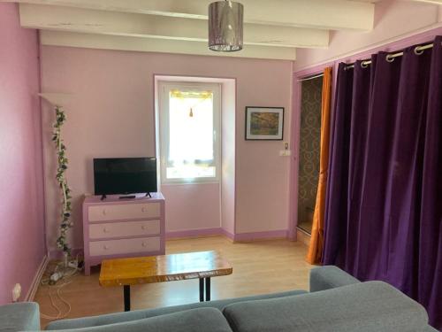 ein Wohnzimmer mit einem Sofa, einem TV und einem Tisch in der Unterkunft Gîte Miss Cardabelle in La Bastide-Pradines
