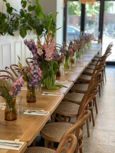 a long wooden table with chairs and vases of flowers at Hotel Alexandra in Copenhagen