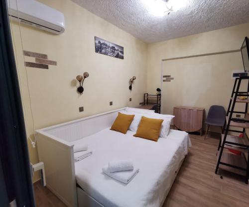 una camera da letto con un letto con lenzuola bianche e cuscini gialli di Serafi Cozy Rooms a Archangelos