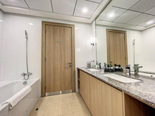 La salle de bains est pourvue de 2 lavabos, d'une baignoire et d'un miroir. dans l'établissement Key View - Villa Gardenia Jebel Ali, à Dubaï
