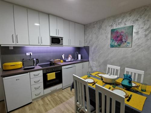 eine Küche mit einem Tisch und eine Küche mit weißen Schränken in der Unterkunft Midori Zlatar in Nova Varoš