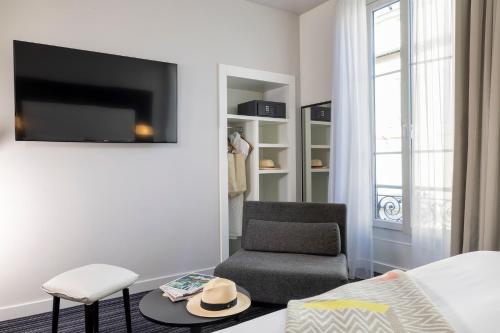 a living room with a chair and a tv at Hotel 66 Nice in Nice