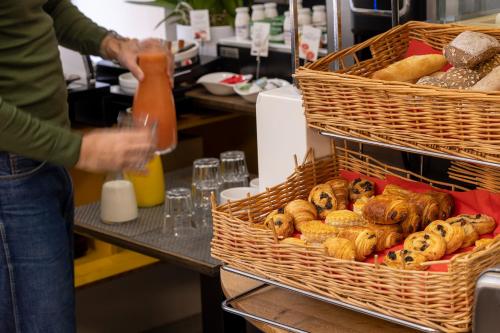 a person standing in a kitchen with baskets of bread at Hotel 66 Nice in Nice