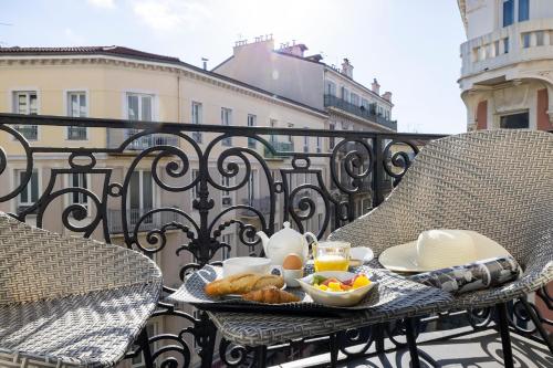 a tray of breakfast food on a table on a balcony at Hotel 66 Nice in Nice
