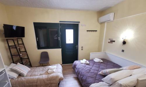 a bedroom with two beds and a door and a chair at Serafi Cozy Rooms in Archangelos
