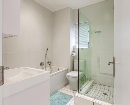 baño blanco con aseo y ducha acristalada en Cosy Butterfly Comforts 2 Bed Top Floor Unit, en Fourways