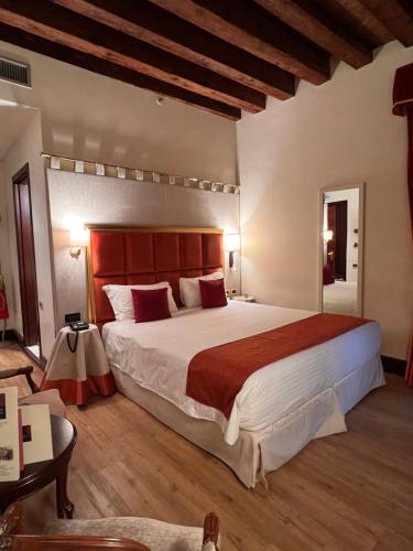 a bedroom with a large bed with a red headboard at Ruzzini Palace Hotel in Venice