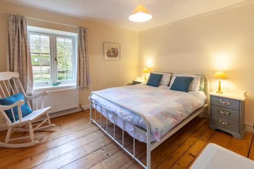 a bedroom with a bed and a chair and a window at Sunny Beck Cottage - Norfolk Cottage Agency in Mundesley