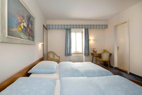 a room with four beds and a table and a window at Hotel Du Lac in Interlaken