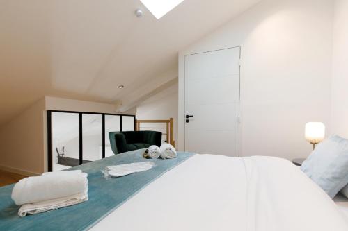 a white bedroom with a large bed with towels on it at Snow YourHostHelper in Cannes