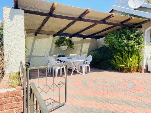 a patio with a table and chairs under a pergola at The Valley, tranquil 3 bedroom home with pool in Midrand