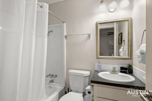 a bathroom with a sink and a toilet and a mirror at Walk To Zilker King Bed Pool Free Parking in Austin