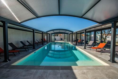 a large swimming pool with chairs and a large window at LE MOUSSE Maison avec piscine/parking/wifi/plages 5kms in Les Mathes