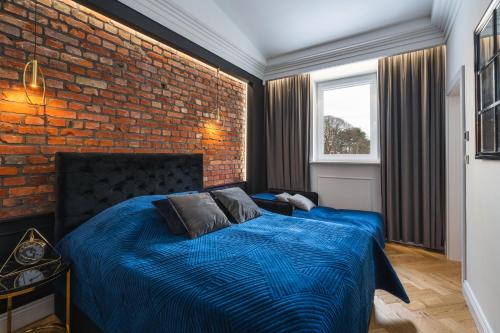 a bedroom with a blue bed with a brick wall at Oliwa Am Calsberg 5a in Gdańsk