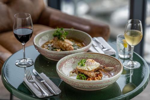 a table with two bowls of food and a glass of wine at Harbour Hotel & Spa Southampton in Southampton