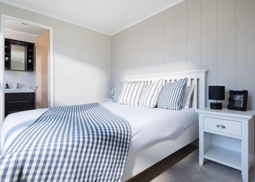 Dormitorio blanco con cama blanca y mesa blanca en Praa Sands Holiday Park, en Saint Hilary