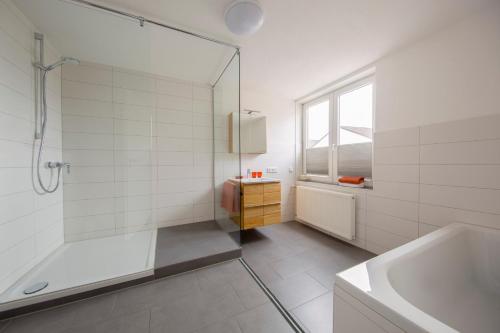 a bathroom with a shower and a tub and a sink at Hotel & Boarding House Schlosserwirt in Mering